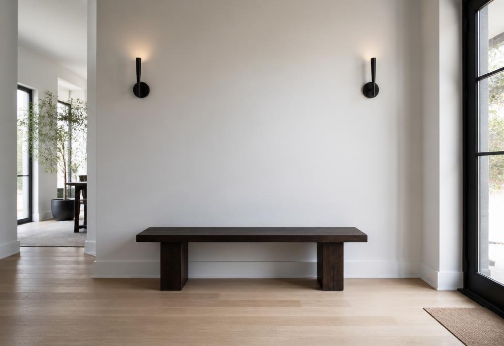 Moderner Eingangsbereich mit weisser Wand, dunkler Bank und Wandleuchten